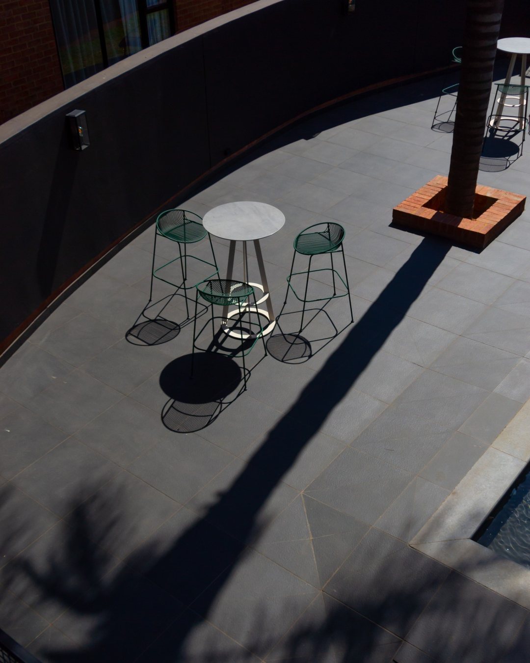 Hyatt House Johannesburg: green bar stools on the terrace in hard afternoon shadow